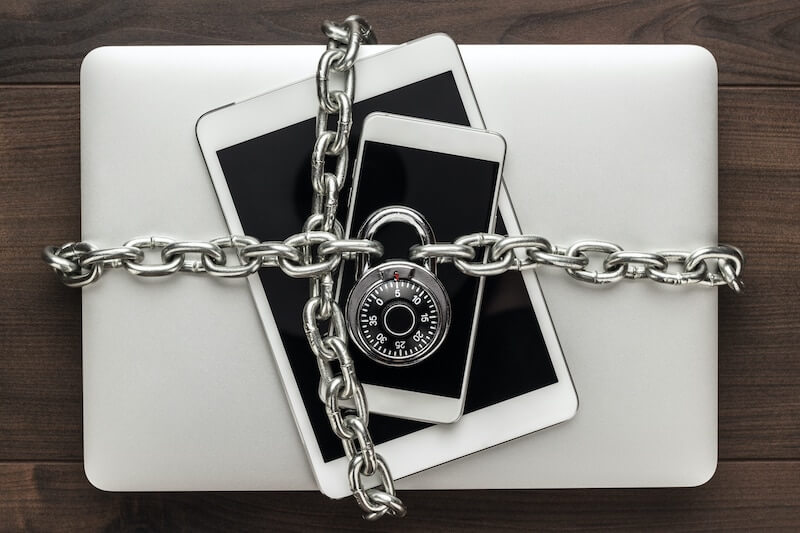 A laptop, iPad, and iPhone protected by a lock and chain. Protected with IT support. 