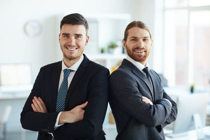 Two happy young men in suits ready to help their IT Clients in Calgary work from home. 
