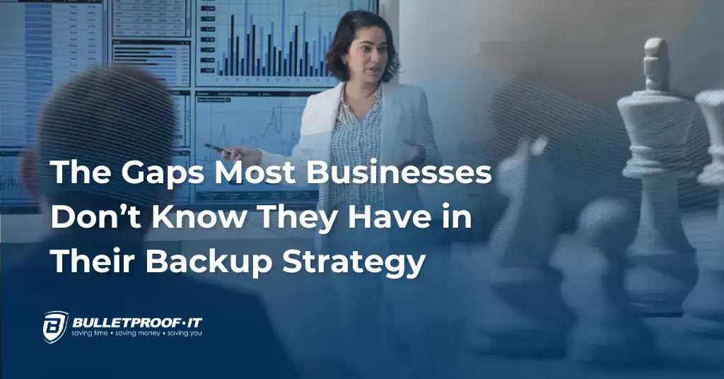 An image with the title of the blog written in white text: The Gaps Most Businesses Don’t Know They Have in Their Backup Strategy. There is a woman in a business setting, with chess pieces superimposed in one corner of the frame.